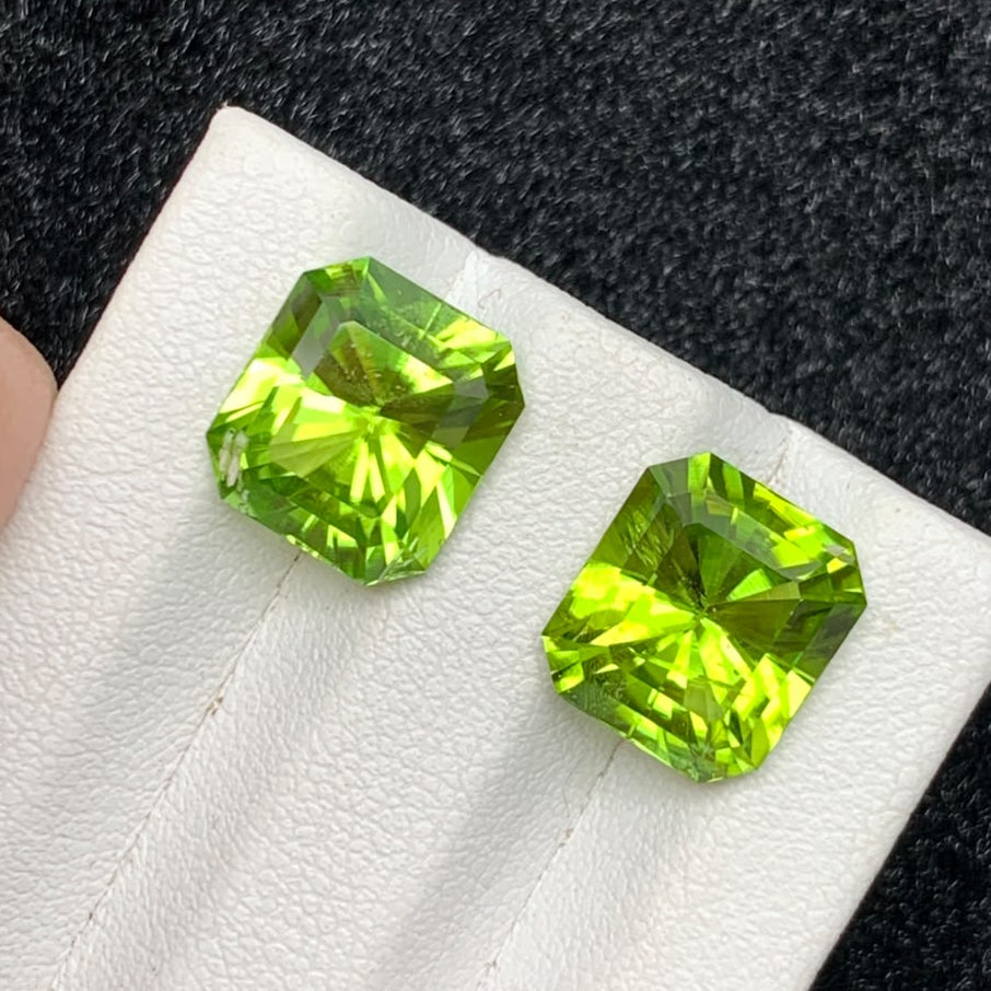 Two green faceted peridot gemstones displayed